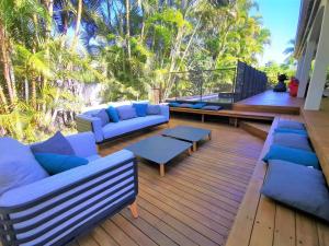 a deck with blue couches and tables and palm trees at Villa Des palmes - piscine privée au bord du Lagon de la Saline in Saint-Paul