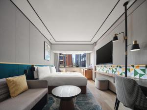 Hilton Garden Inn Hangzhou West Lake في هانغتشو: غرفه فندقيه بسرير واريكه
