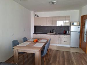 a kitchen with a wooden table and blue chairs at HomeViza in Yambol