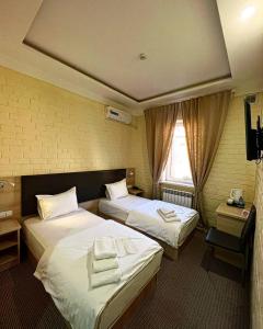 タシュケントにあるAl Arda HOTELのベッド2台と窓が備わるホテルルームです。