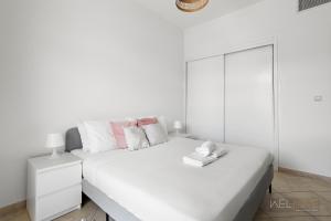 a white bedroom with a large white bed and a mirror at WelHome - Serene Bliss: Regent House 2 Studio Haven in Dubai