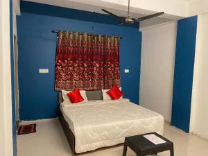 Schlafzimmer mit blauen Wänden und einem Bett mit roten Kissen in der Unterkunft Hotel Kings Inn in Nagpur