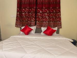 Bett mit zwei roten Kissen vor einem Vorhang in der Unterkunft Hotel Kings Inn in Nagpur
