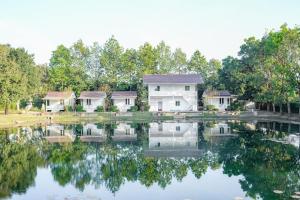 una fila de casas reflejadas en un lago en อาลาแคมป์, en Ban Mo Maklua