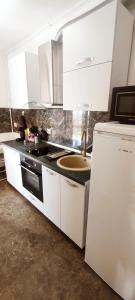 a kitchen with white cabinets and a sink and a stove at BELLE VIEW SINAIA in Sinaia