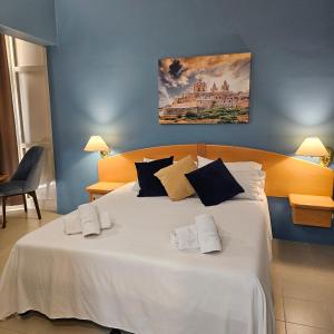 sypialnia z dużym białym łóżkiem z ręcznikami w obiekcie La Playa Hotel w mieście Marsalforn