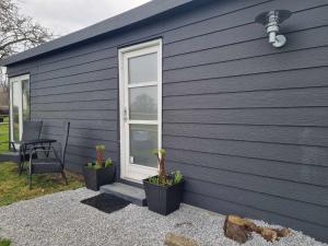 a blue house with two potted plants next to a window at Falsterly Glamping in Horbelöv