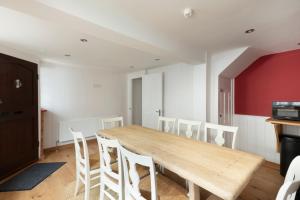 a dining room with a wooden table and white chairs at Stag Cottage, Sea wall in Whitstable