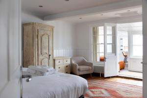 a bedroom with a bed and a chair and a dresser at Stag Cottage, Sea wall in Whitstable