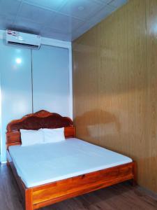 1 dormitorio con cama de madera con sábanas blancas en Homestay Nguyễn Hùng en Rạch Tàu