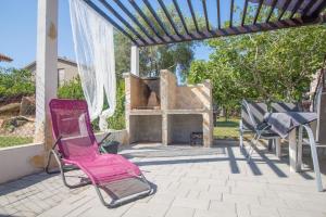 Wohnung in Privlaka mit Terrasse, Grill und Garten في بريفلاكا: كرسي وردي للجلوس على فناء مع موقد