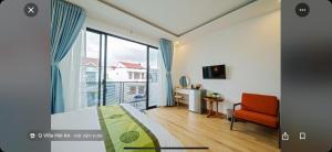 a bedroom with a bed and a window and a chair at Q Villa Hoi An in Hoi An