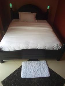 a bed with a black frame and a white bedvisor at Suzie hotel 15 rubaga road kampla in Kampala