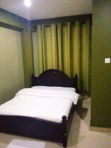 a bed sitting in a room with a curtain at Suzie hotel 15 rubaga road kampla in Kampala