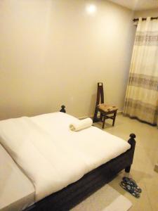 een slaapkamer met een bed en een stoel erin bij Suzie hotel 15 rubaga road kampla in Kampala