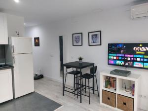 ein Wohnzimmer mit einem Tisch, einem TV und einem Kühlschrank in der Unterkunft Los Pinos 8 in Benahavís