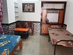 um quarto com duas camas e uma mesa em Bava guest house em Tiruvannamalai