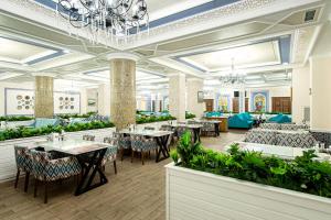 restauracja ze stołami i krzesłami oraz żyrandolem w obiekcie Shymkent Grand Hotel w mieście Szymkent