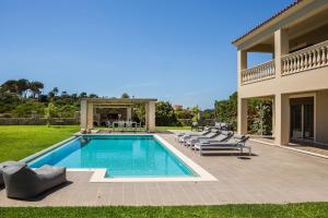 a swimming pool with lounge chairs and a house at Villa Infinity Blue, Svoronata Minia- KefaloniaCollections in Svoronata