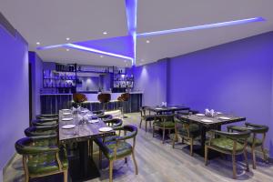 Hotel The Rising في أودايبور: غرفة طعام مع طاولات وكراسي وجدران أرجوانية