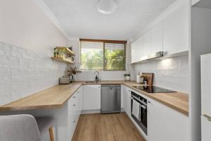 une cuisine avec des placards blancs et un comptoir en bois dans l'établissement Terrific & Tranquil! 1Bed/1Bath/Balcony~ Clayfield, à Brisbane