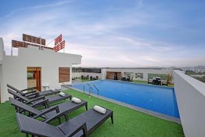 a pool on the roof of a house with lounge chairs at Hotel The Rising in Udaipur