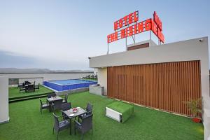 een dakterras met tafels en stoelen en een zwembad bij Hotel The Rising in Udaipur