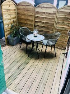 een patio met een tafel en stoelen op een houten terras bij Appartement 23 in Reims