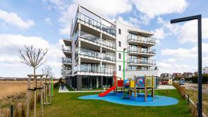 a apartment building with a playground in front of it at Apartamenty Sun & Snow Westin House Resort in Kołobrzeg