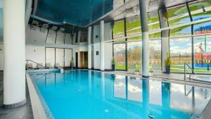 a large swimming pool with blue water in a building at Apartamenty Sun & Snow Westin House Resort in Kołobrzeg