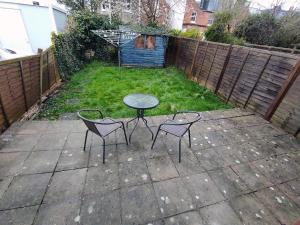 a patio with a table and two chairs and a dog at Osney Hazel Studio - Self Contained Studio Flat in Oxford