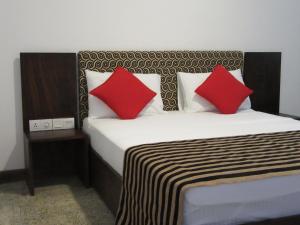 a bedroom with a bed with two red pillows at Miridiya Resort in Yatiyantota