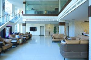 een lobby met mensen op banken in een gebouw bij RAS Hotels in Kumbakonam