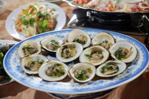 un plato azul y blanco de ostras sobre una mesa en Homestay Nguyễn Hùng en Xóm Rạch Tàu