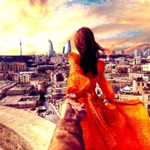 um homem tirando uma foto de uma mulher no topo de uma cidade em Soffia Hotel Baku em Baku