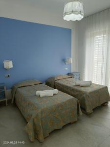 - 2 lits dans une chambre avec un mur bleu dans l'établissement Villa Mariana Bed and Breakfast, à Saluces