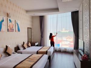 Hà Nám的住宿－Tiến Lộc Plaza Hotel，站在酒店房间,望向窗外的女人