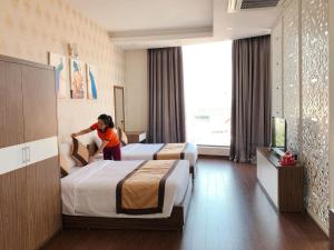 uma jovem num quarto de hotel com duas camas em Tiến Lộc Plaza Hotel em Hà Nám