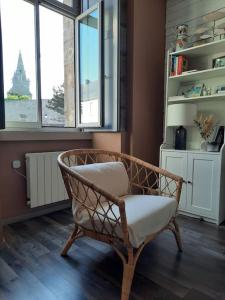 een rieten stoel in een kamer met 2 ramen bij La Cabane du Roc in Granville