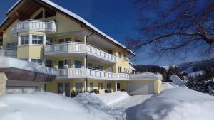 un gran edificio amarillo con nieve alrededor en Deluxe Ferienwohnung Schwarzwald, 8 Personen, 140 qm, Haus Sonnenschein, en Todtnau