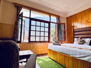 ein Schlafzimmer mit einem Bett und einem großen Fenster in der Unterkunft Hotel Suraj Retreat inn in Manali