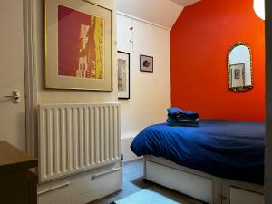 a bedroom with a bed and an orange wall at Comfy child/dog friendly garden flat heart Camden in London