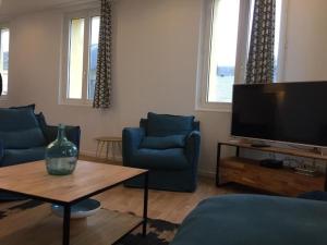 a living room with two blue chairs and a television at Le Sémaphore in Fécamp