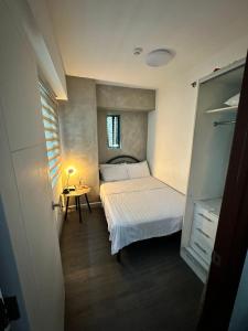 Dormitorio pequeño con cama y mesa en The Pearl - BGC McKinley Park 2BR en Manila