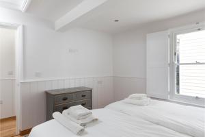 two beds in a white room with towels on them at Stag Cottage, Sea wall in Whitstable