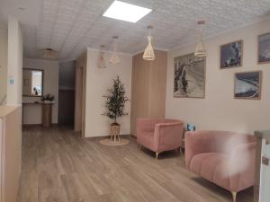 una sala de estar con 2 sillas rosas y un árbol en Hostal Garamar, en Benicàssim