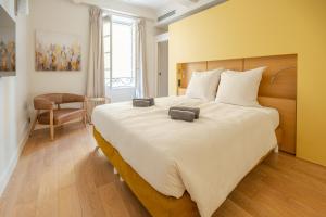 - une chambre avec un grand lit blanc et une chaise dans l'établissement Beau Clocher, à Saint-Tropez