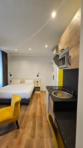 a bedroom with a bed and a kitchen with a sink at HOTEL PARIS PANAM-PERE LACHAISE-PLACE GAMBETTA-HOPITAL TENON-REPUBLIQUe in Paris