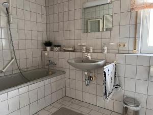 uma casa de banho em azulejos brancos com um lavatório e uma banheira em moderne 2-Zimmer Wohnung in Rastatt em Rastatt