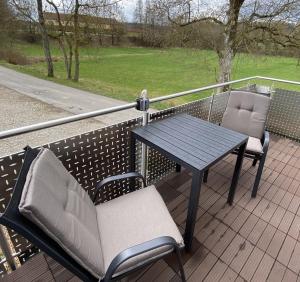 2 sillas y una mesa en un balcón con mesa y sillas en Ferienwohnung II en Schnelldorf